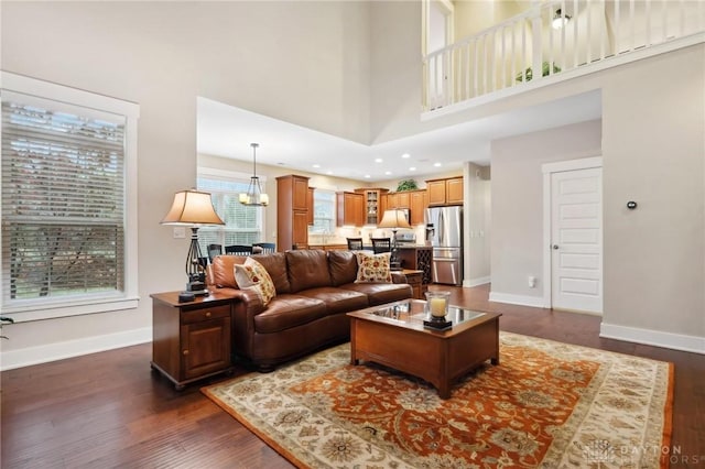 living room featuring a chandelier, dark wood-type flooring, and a high ceiling