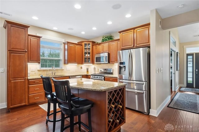 kitchen with a center island, sink, decorative backsplash, dark hardwood / wood-style flooring, and stainless steel appliances