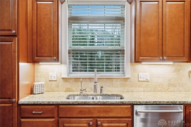 kitchen with stainless steel dishwasher, a healthy amount of sunlight, light stone counters, and sink