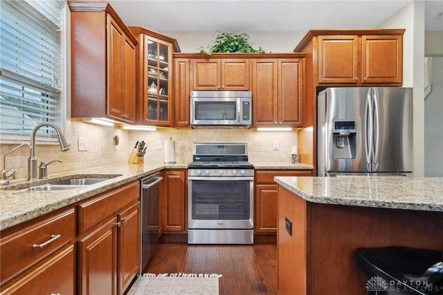 kitchen with light stone counters, dark hardwood / wood-style flooring, sink, and appliances with stainless steel finishes