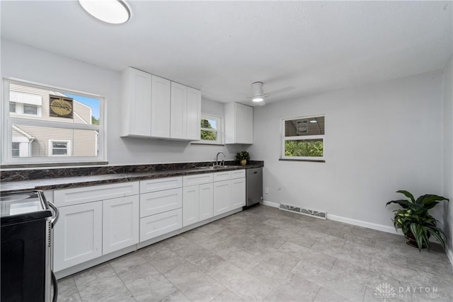 kitchen featuring range, sink, stainless steel dishwasher, ceiling fan, and white cabinetry