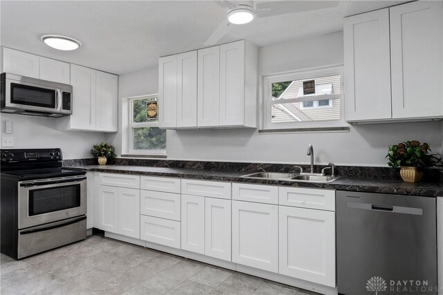 kitchen with sink, white cabinetry, stainless steel appliances, and dark stone counters