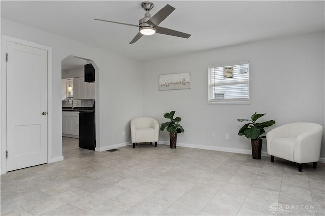 living area featuring ceiling fan and sink