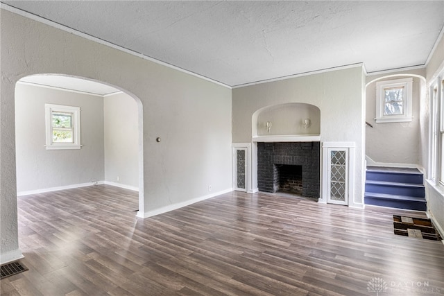 unfurnished living room with dark hardwood / wood-style flooring, a brick fireplace, and ornamental molding