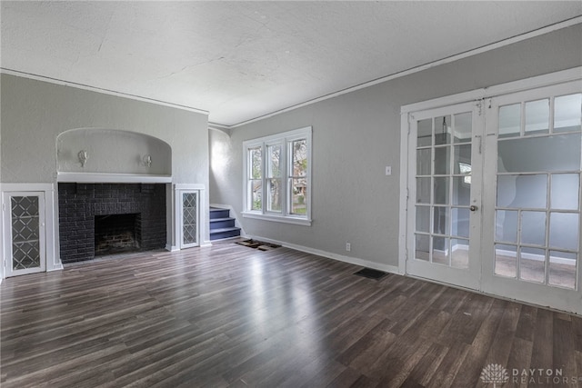 unfurnished living room featuring a fireplace, ornamental molding, a textured ceiling, and dark wood-type flooring