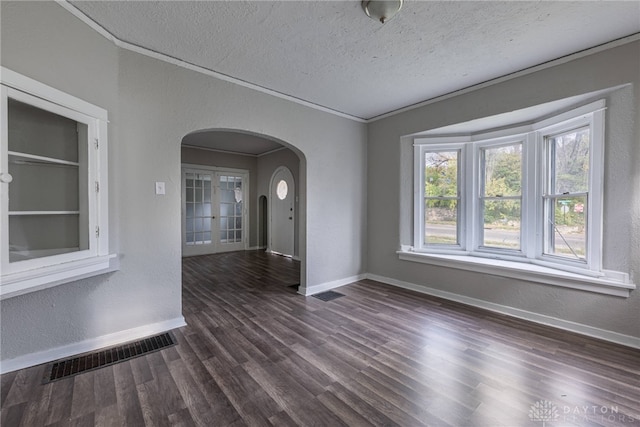 spare room with a textured ceiling, dark hardwood / wood-style floors, built in features, and crown molding