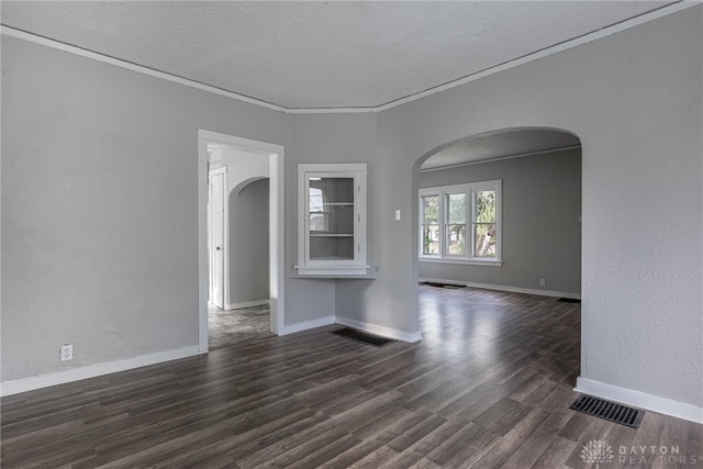 empty room featuring ornamental molding and dark wood-type flooring