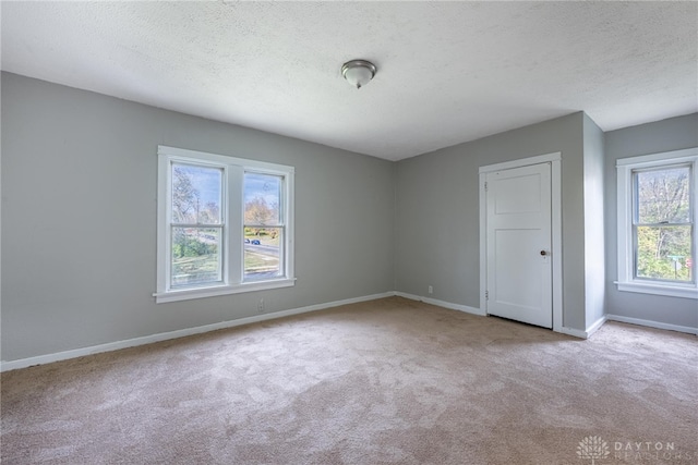 carpeted empty room featuring a textured ceiling and a wealth of natural light