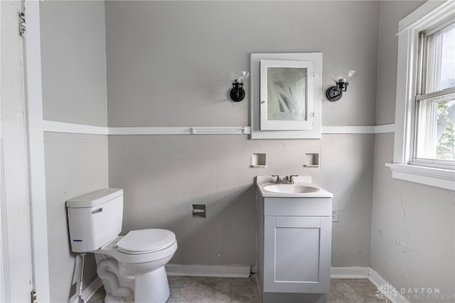 bathroom with tile patterned floors, vanity, toilet, and tile walls