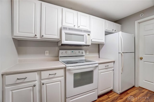 kitchen with white cabinets, hardwood / wood-style floors, and white appliances