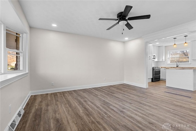 unfurnished living room featuring light wood-type flooring, ceiling fan, and sink