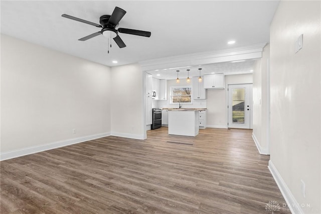 unfurnished living room featuring hardwood / wood-style flooring, ceiling fan, and sink