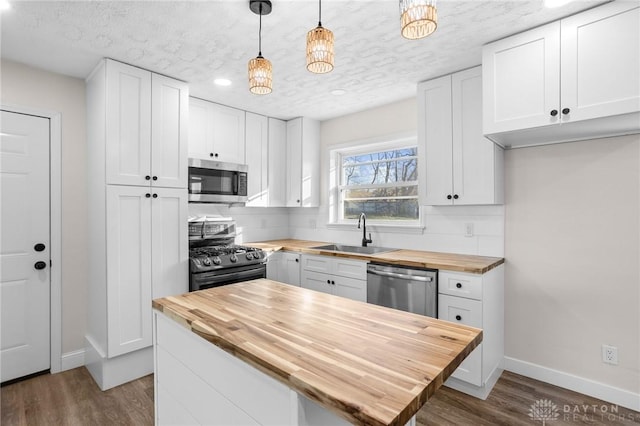 kitchen featuring wood counters, appliances with stainless steel finishes, and white cabinetry