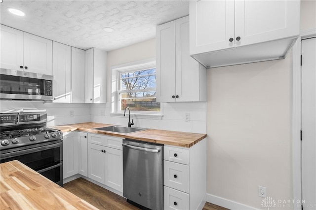 kitchen featuring wooden counters, appliances with stainless steel finishes, a textured ceiling, sink, and white cabinets