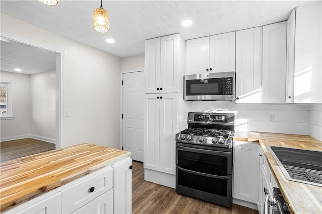 kitchen with decorative light fixtures, wood counters, white cabinetry, and appliances with stainless steel finishes