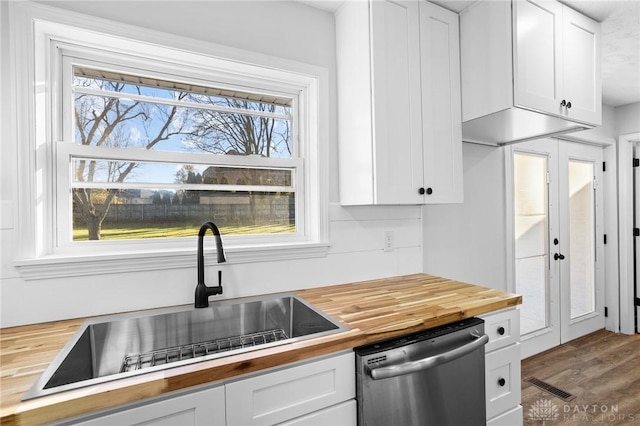 kitchen with sink, wood-type flooring, dishwasher, white cabinetry, and butcher block counters