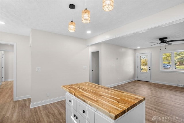 kitchen featuring wooden counters, a kitchen island, pendant lighting, light hardwood / wood-style flooring, and white cabinetry