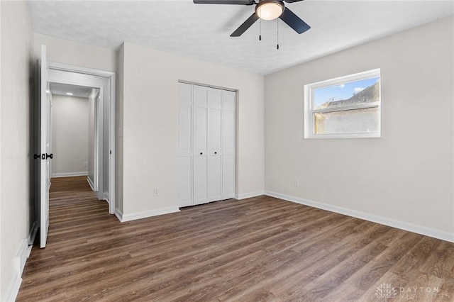 unfurnished bedroom with ceiling fan, a closet, and dark wood-type flooring