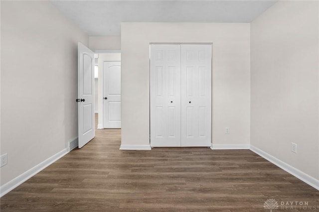 unfurnished bedroom featuring dark hardwood / wood-style floors and a closet