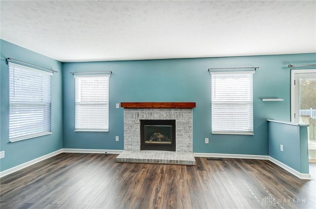 unfurnished living room with a fireplace, dark hardwood / wood-style flooring, and a textured ceiling