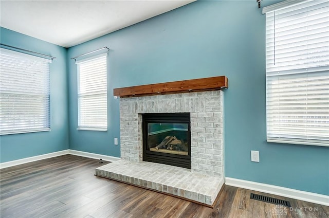 unfurnished living room featuring dark hardwood / wood-style flooring and a brick fireplace