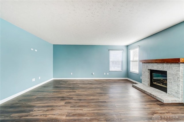 unfurnished living room with a textured ceiling, dark hardwood / wood-style floors, and a brick fireplace