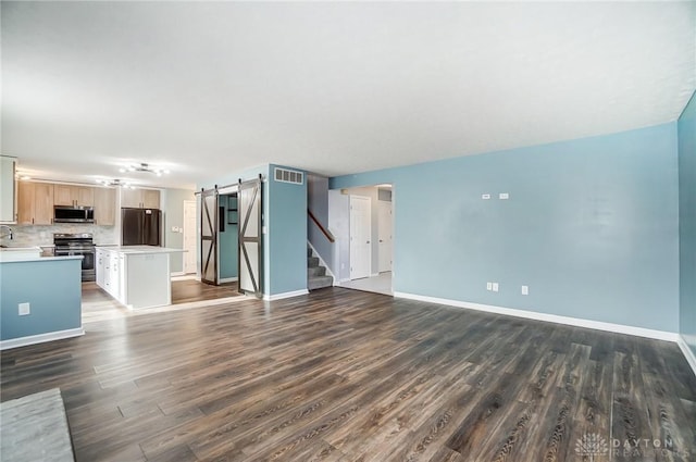 unfurnished living room featuring a barn door, dark hardwood / wood-style flooring, and sink