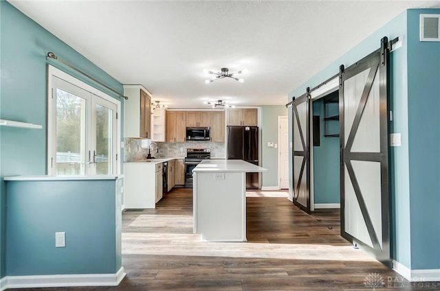 kitchen with sink, light hardwood / wood-style flooring, a barn door, appliances with stainless steel finishes, and a kitchen island