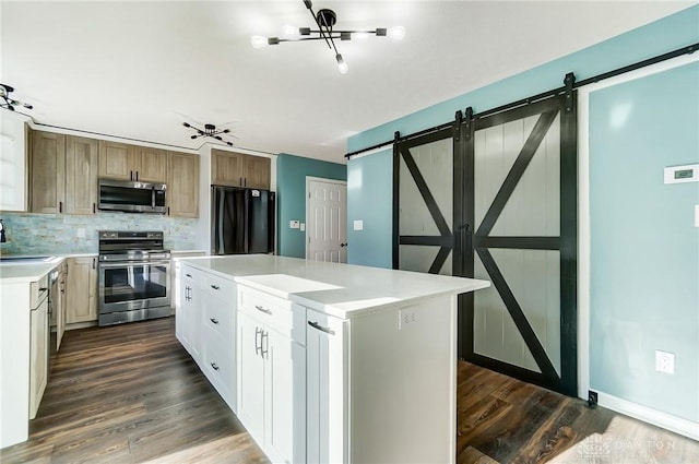 kitchen featuring appliances with stainless steel finishes, a barn door, a center island, and white cabinetry