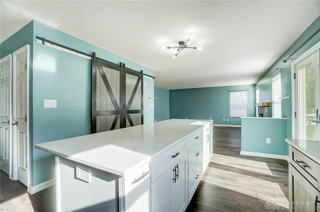 kitchen with white cabinets, a center island, a barn door, and hardwood / wood-style flooring