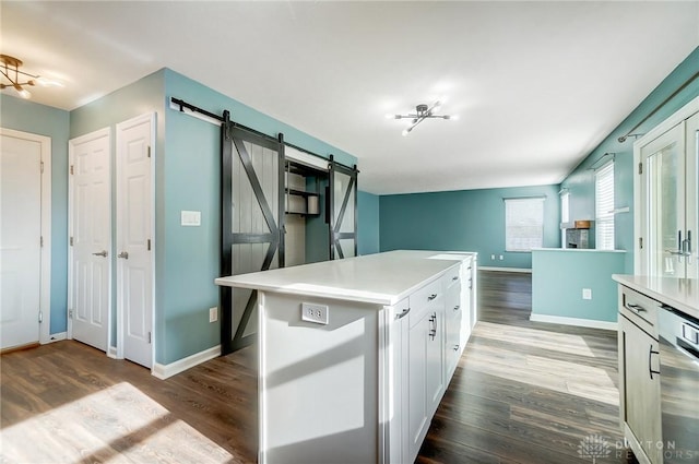 kitchen with a barn door, a center island, white cabinetry, and hardwood / wood-style flooring