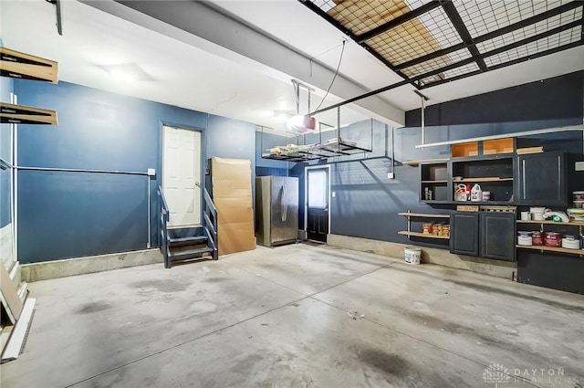 garage with a garage door opener and stainless steel refrigerator