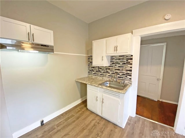 kitchen with backsplash, white cabinetry, sink, and light wood-type flooring