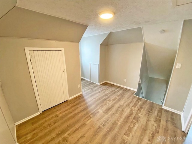 bonus room with hardwood / wood-style floors, a textured ceiling, and lofted ceiling