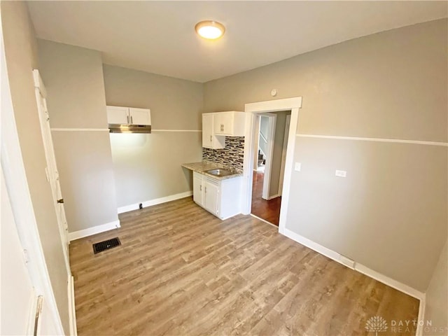 kitchen featuring white cabinets, decorative backsplash, sink, and light hardwood / wood-style flooring