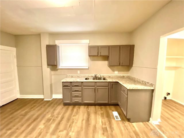 kitchen with gray cabinetry, light hardwood / wood-style floors, and sink