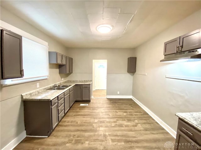 kitchen featuring light stone countertops, sink, and light wood-type flooring