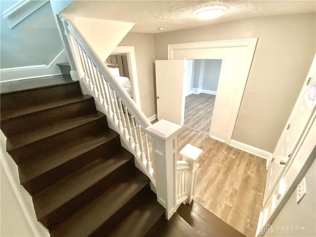 stairway featuring wood-type flooring and a textured ceiling