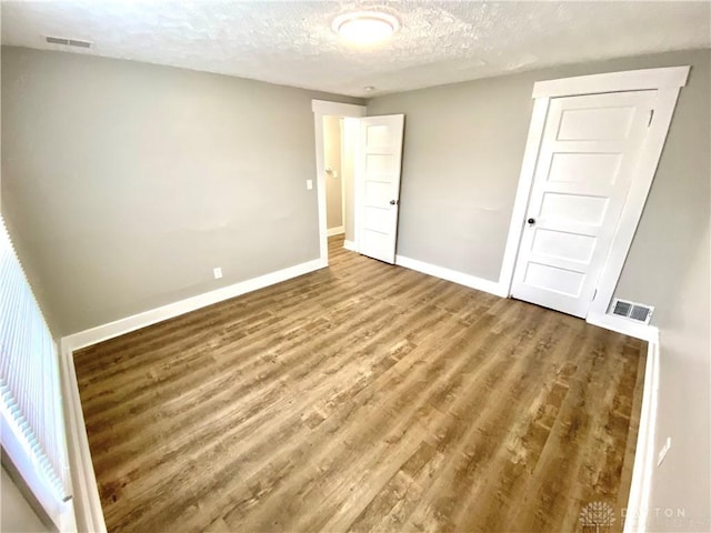 unfurnished bedroom featuring a closet, wood-type flooring, and a textured ceiling