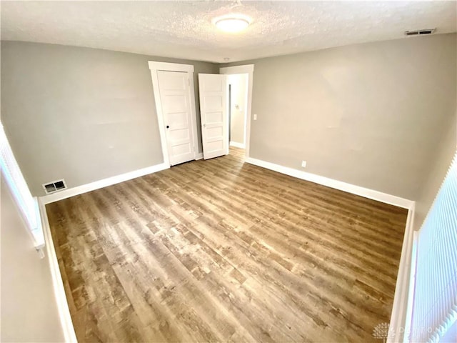 unfurnished bedroom featuring a textured ceiling, hardwood / wood-style flooring, and a closet