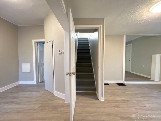 stairs with hardwood / wood-style floors and a textured ceiling