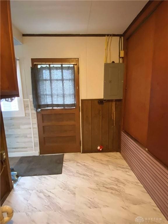 doorway featuring electric panel, wood walls, and crown molding