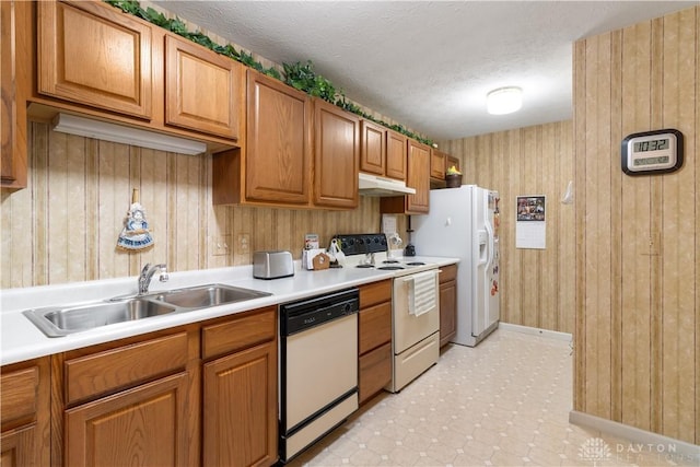 kitchen with wood walls, sink, white appliances, and a textured ceiling