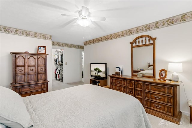 bedroom with ceiling fan, light colored carpet, a closet, and a walk in closet