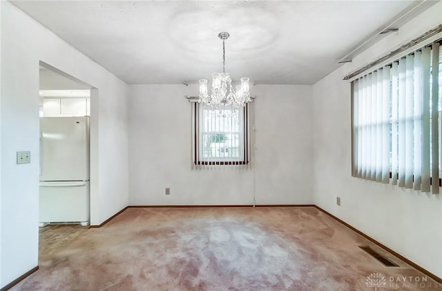 carpeted spare room with a notable chandelier