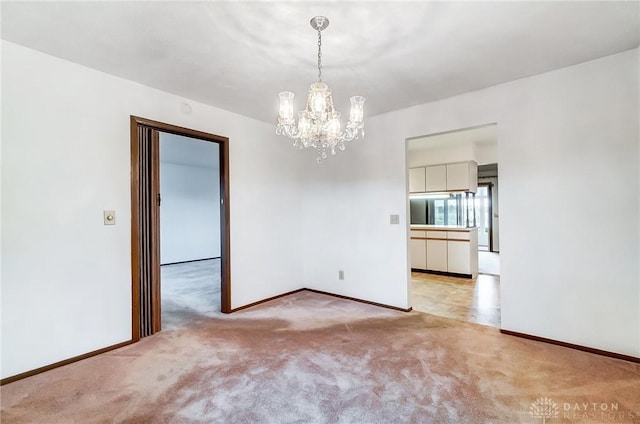 carpeted spare room with a notable chandelier