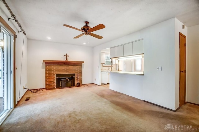 unfurnished living room featuring light carpet, a brick fireplace, and a wealth of natural light