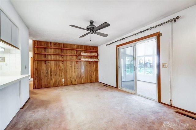 carpeted spare room featuring ceiling fan and wood walls