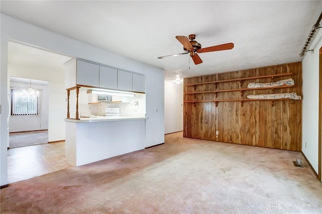 unfurnished living room with light carpet, ceiling fan, and wooden walls