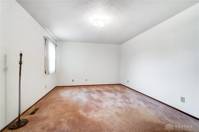 empty room with carpet flooring and a textured ceiling